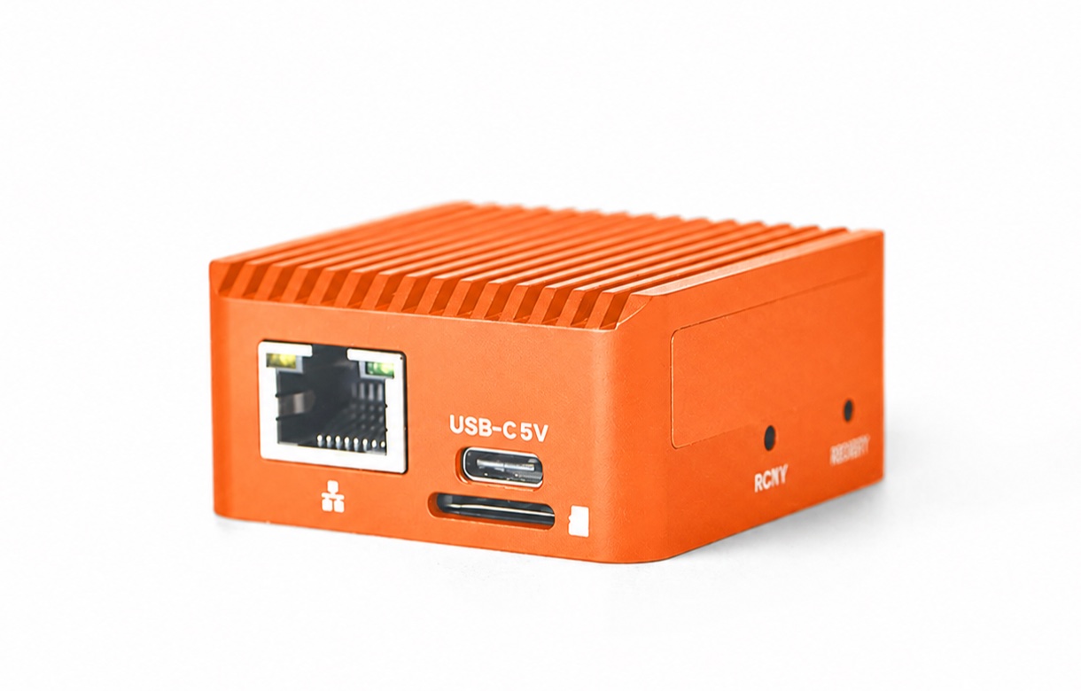 The SesamIQ plug-in device — a palm-sized orange metal box with a finned heatsink top, an Ethernet jack, and a USB-C port.